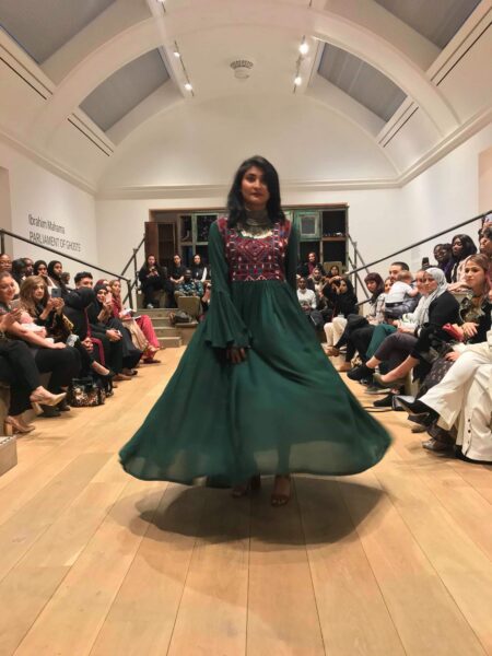 Model walking down catwalk in an emerald green dress by Electric Bazaar