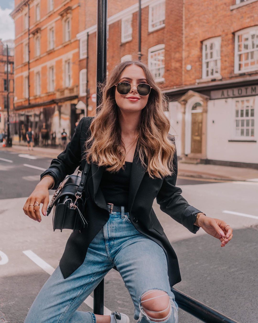 Model wearing leather jacket and ripped denim jeans in Manchester streets