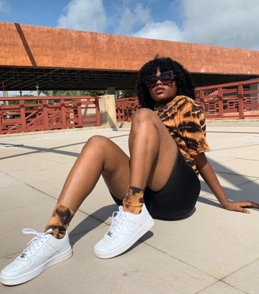 Woman in white sneakers with tie-dye t-shirt and black shorts