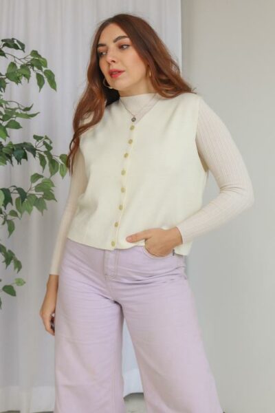 Woman wearing cream vintage sweater vest and lavender trousers