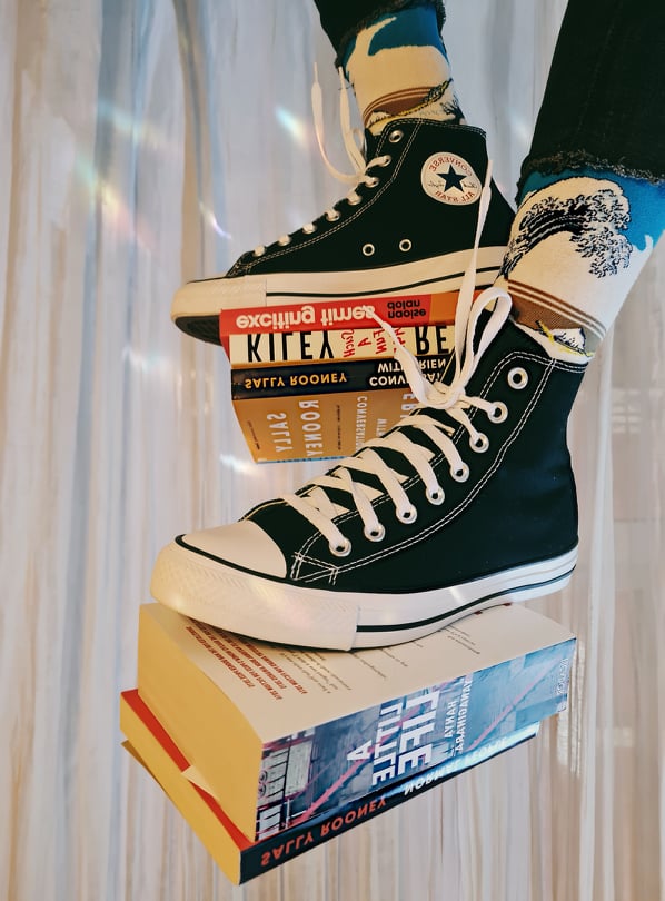Martina's bookstagram bookshelf pic with a shot of books balanced on her trainers