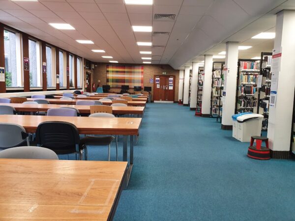 A photo depicting a library with some bookshelves and tables..
