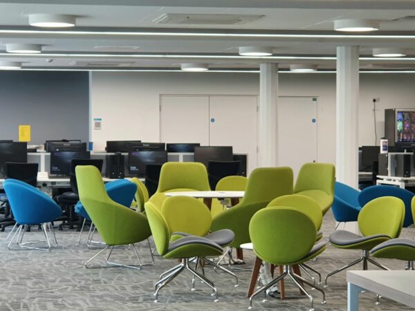 A photo of the Lime cafe in which yu can see tables, green and blue chairs, and a computer cluster in the background