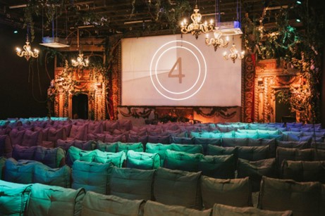 a large screen indoors with seating and chandeliers