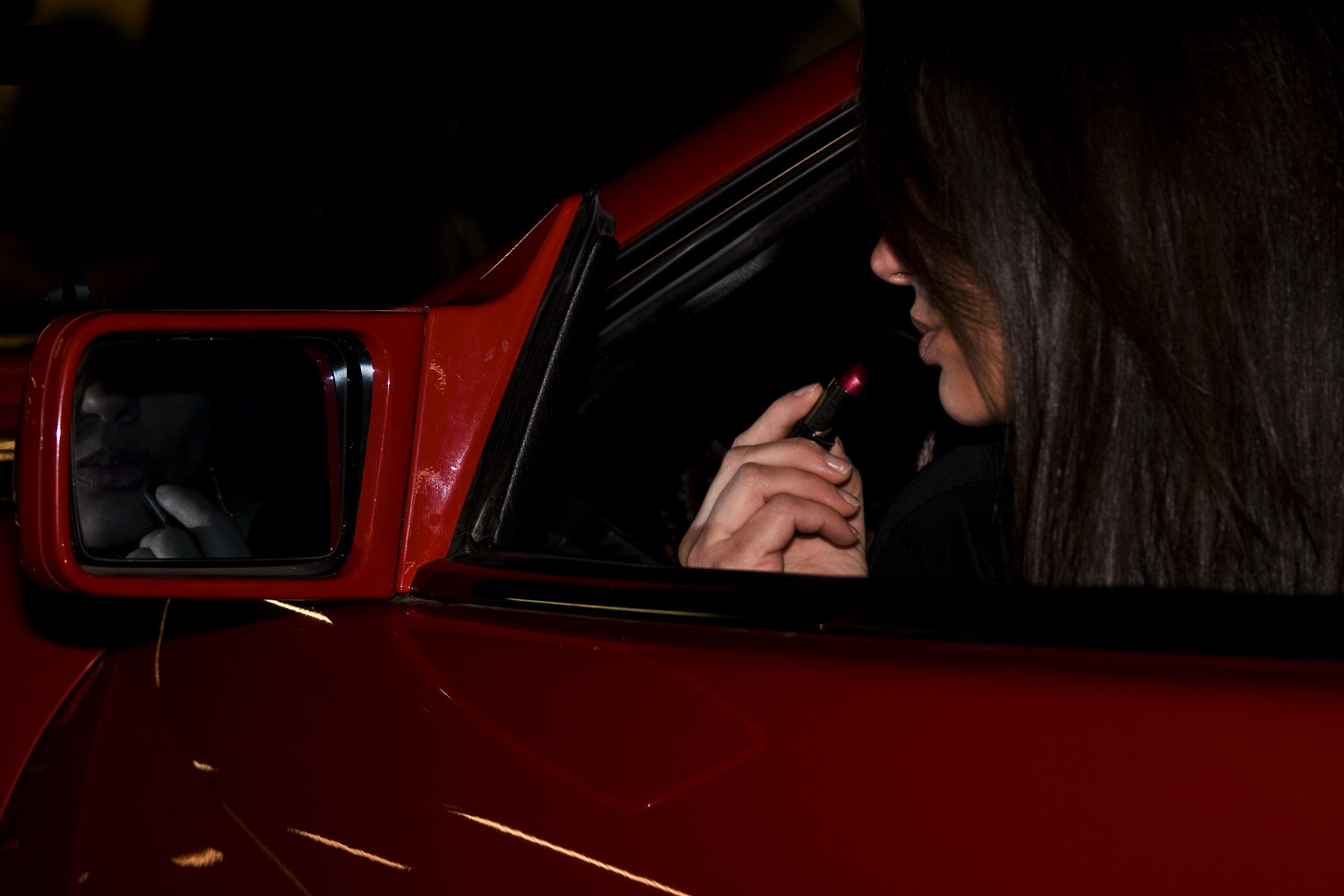 women in car putting on lipstick