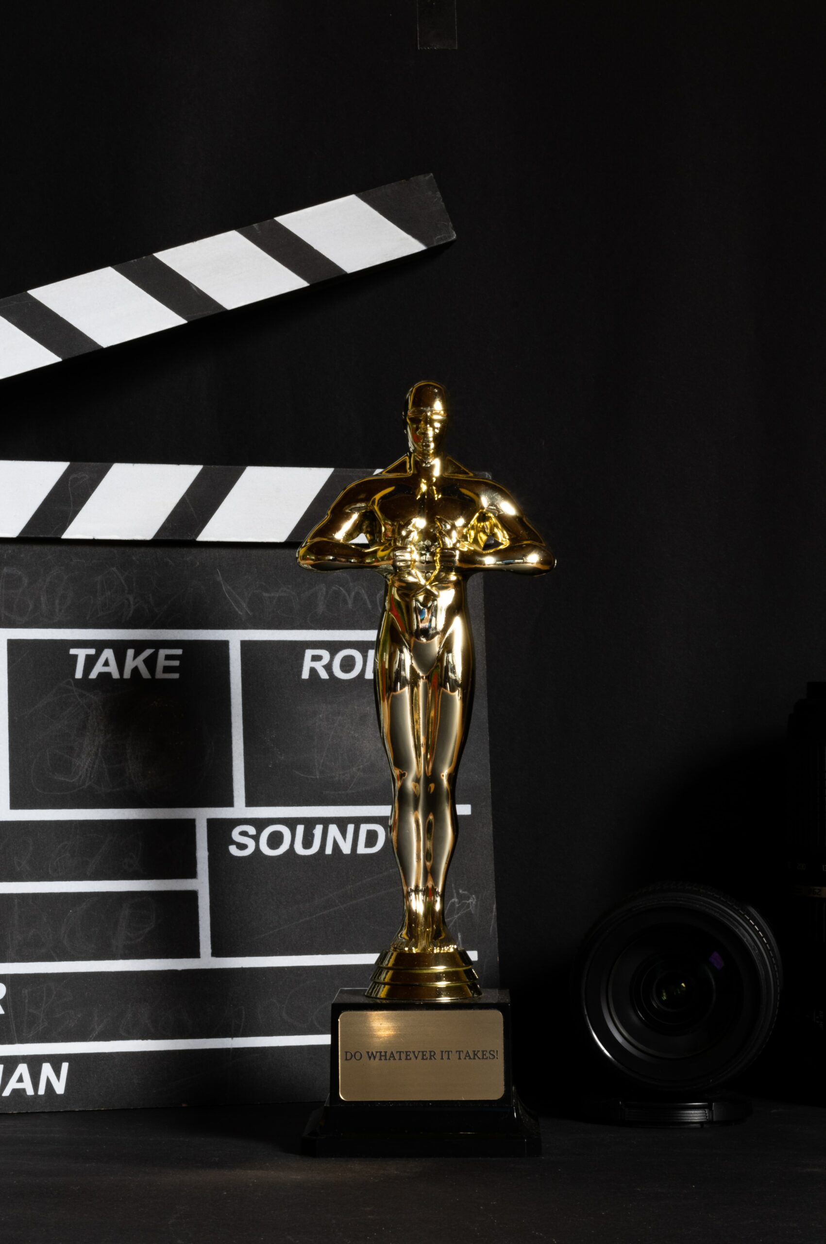 Photo of an Oscar's trophy in front of a black clapperboard with white writing on