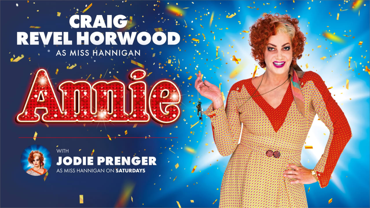 Craig Revel Horwood dress as Miss Hannigan poses infront of beaming light next to text advertising the Uk tour of Annie