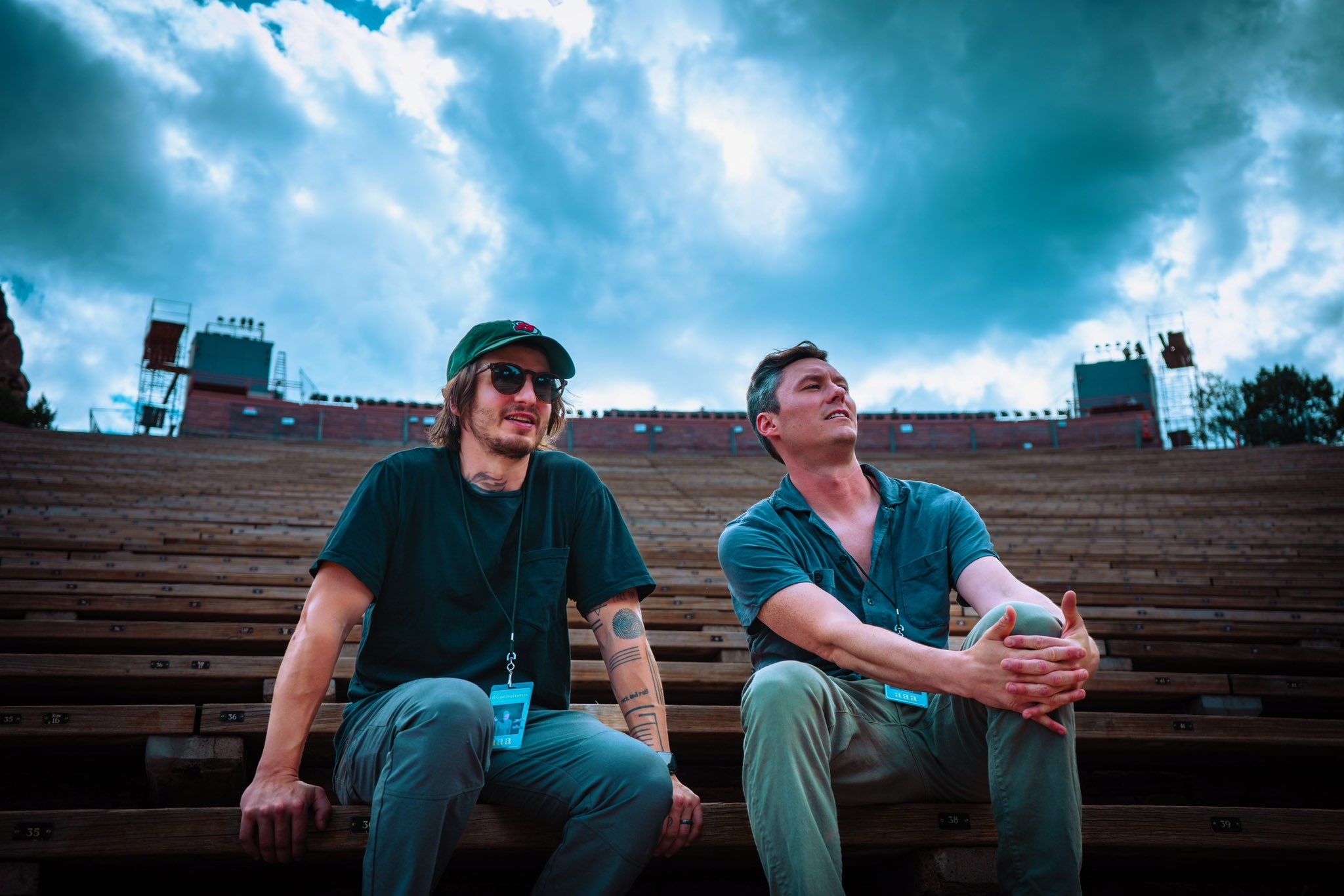 The Front Bottoms sit in an empty amphiteatre. Matt Uychich is on the left in a cap and sunglasses. Brian Sella is on the right.