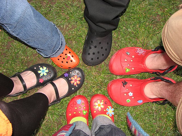 Birdseye view of Crocs in different styles worn on grass