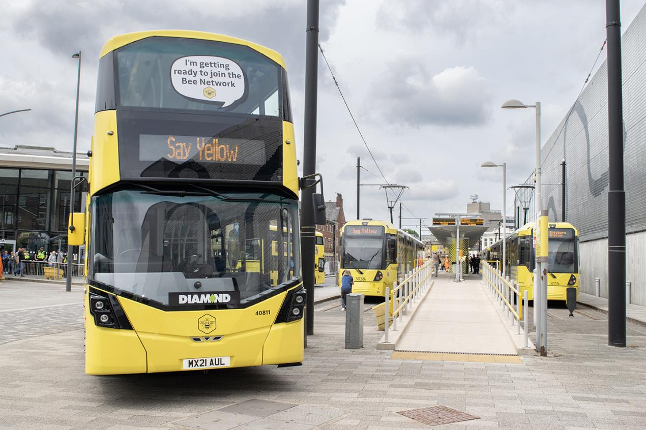 Yellow Bee Network bus positioned outside bus terminal station saying, "Say Yellow."