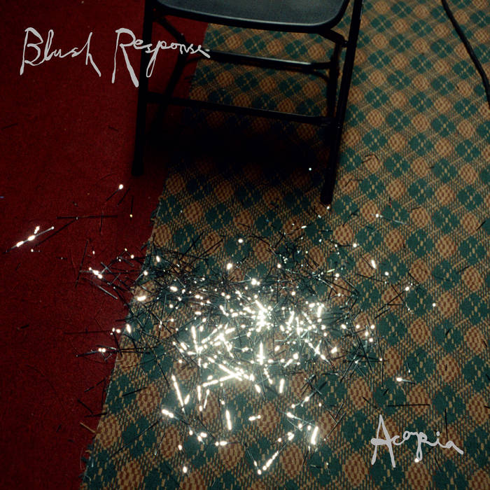 Album cover for Acopia's 'Blush Response'. Downwards looking shot of a tartan carpet with the edge of a chair and slightly over exposed silver tinsel sprawled across the floor.